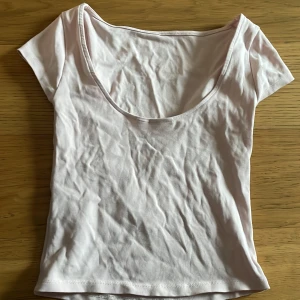 Ljusrosa topp från Gina Tricot - Säljer en ljusrosa topp från Gina Tricot i mjuk bomull. Toppen har korta ärmar, rundad djup bak och en croppad passform. Perfekt för dig som gillar enkla och stilrena plagg med en feminin touch.
