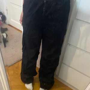 Svarta parachute pants med snörning - Svarta parachutepants med avslappnad passform och dragsko i midjan.Perfekta för en chill och streetig look.