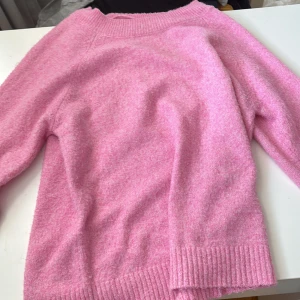 Rosa stickad tröja från Vero Moda - Supermjuk rosa stickad tröja från Vero Moda i storlek XS. Tröjan har en klassisk rund halsringning, ribbade muddar och lång ärm. Perfekt för dig som vill ha en färgklick i garderoben och gillar en avslappnad men ändå söt stil.