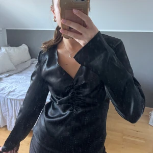 Svart satin blus från Gina - Supersnygg svart blus från Gina tricot. Blusen är plisserat framtill med slitsar på ärmarna och en gömd dragkedja på vänster sida. Den är endast använd ett fåtal gånger så är i fint skick🩷🩷