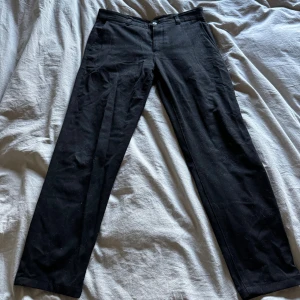 Svarta kostymbyxor från Zara - Klassiska svarta kostymbyxor från Zara med rak passform och diskret knappstängning. Byxorna är tillverkade i ett mjukt tyg som känns bekvämt och stilrent. Perfekta för en clean och snygg look.