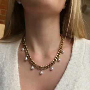 Guldpläterat halsband med droppformade pärlor - Elegant halsband i guldpläterat rostfritt stål – finns även i silverfärgad variant. Matchande örhängen finns i en separat annons.  Smycket är 9 mm brett och har en justerbar längd mellan 38–43 cm, vilket gör att det passar perfekt oavsett stil och tillfälle.. De nickelfria och handgjorda