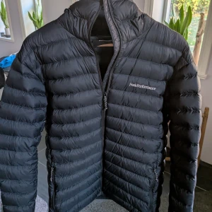 Svart dunjacka Peak Performance - Snygg svart dunjacka från Peak Performance med huva och dragkedja framtill. Jackan är sparsamt använd under en kort period, så inga defekter förekommer. Nypris 2899kr. Priset kan diskuteras 