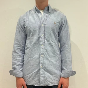 Blå slim fit skjorta från Polo Ralph Lauren - Blå Ralph Lauren skjorta || Storlek S (Slim Fit) || Skjotan är i bra skick, däremot förekommer en fläck som syns på bild 5 || Modellen på bilden är 170cm och väger 62kg || Tveka inte på att höra av dig vid frågor eller funderingar 