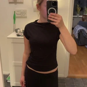 Svart kortärmad t-shirt - En enkel svart t-shirt med korta ärmar och rund hals. Modellen är figurnära och passar perfekt till jeans eller mjukisbyxor. T-shirten har en klassisk look och är lätt att matcha med andra plagg.