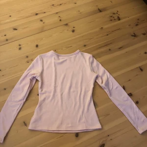 Ljusrosa fleecefodrad tröja från Dazy - Mysig ljusrosa långärmad tröja från Dazy med fleecefoder på insidan. Tröjan har en enkel, figurnära passform och är perfekt för kyligare dagar. Tillverkad i mjuk polyesterblandning för extra komfort.