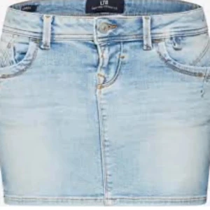 Ljusblå jeanskjol från LTB - Ljusblå jeanskjol från LTB med klassisk femficksdesign, bälteshällor och knapp- samt dragkedjestängning framtill. Kjolen har en rak, kort passform och snygga bakfickor med dekorativa sömmar. Perfekt för en avslappnad och trendig look.