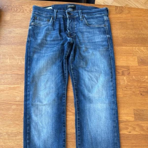 Blå slim fit jeans Jack & Jones - Snygga blå jeans från Jack & Jones i modellen Slim/Glenn. Jeansen har klassisk femficksdesign, normalhög midja och smal passform. Materialet är mjukt denim i bomull med lite stretch för extra komfort. Perfekta för dig som gillar en stilren och modern look.