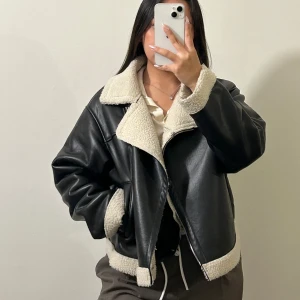 Svart teddyjacka från Gina Tricot - Säljer en svart teddyjacka från Gina Tricot med krage och detaljer i beige fuskpäls. Materialet är syntet med skinnlook och mjuk teddy på insidan och vid kanterna. I superbra skick, skriv om flera bilder önskas 🥰