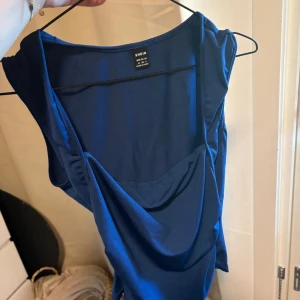 Blå ärmlös topp  - Snygg blå topp från SHEIN i storlek M. Modellen är ärmlös med draperad detalj framtill som ger en cool och modern look. Perfekt för dig som gillar stilrena och trendiga plagg. Materialet känns mjukt och följsamt mot kroppen.