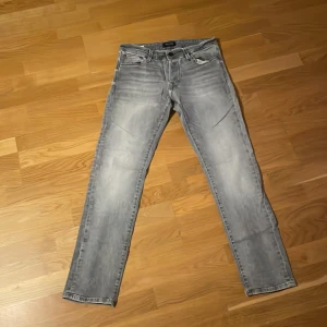 Ljusgrå slim jeans Jack & Jones Glenn - Säljer ett par ljusgrå slim fit jeans från Jack & Jones, modell Glenn. Jeansen har klassisk femficksdesign, snyggt slitna detaljer och raka ben. Perfekta för dig som gillar en smalare passform och stilren look.