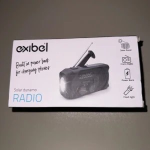 Exibel Solar Dynamo Radio - Väderbeständig dynamoradio med solceller, AM/FM-radio, inbyggd 2000 mAh powerbank för laddning av telefoner, LED-lampa och siren. Perfekt för camping och nödsituationer. Kompakt design (145x60x75 mm) och flera laddningsalternativ: solpanel och vev. Oöppnad förpackning, nyskick.