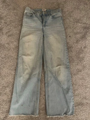 Ljusblå wide jeans från lager 157 - Säljer ett par ljusblå jeans från lager 157 med raka, vida ben och rå kant nertill. Klassisk femficksmodell med dragkedja och knapp. Jeansen har en avslappnad passform och är tillverkade i slitstarkt denimtyg. Fläckarna går inte bort därav priset