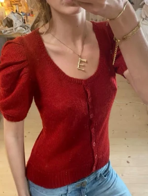 Röd kofta med puffärm med mohair - Snygg röd kofta från Gina Tricot med puffiga korta ärmar och rund halsringning. Tröjan har knappar framtill och är stickad i en mjuk mix av rami, akryl och mohair. Perfekt till jeans eller kjol för en trendig look.