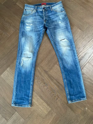 Jack & Jones Slim Glenn blå jeans - Säljer ett par blå jeans från Jack & Jones, modell Slim Glenn. Jeansen har slitna detaljer och små färgstänk på framsidan, klassisk femficksdesign och knappgylf. Passformen är slim och materialet är jeans i bomull. RIKTIGT FETTA💸💸💸
