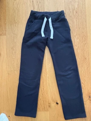 Mörkblå mjukisbyxor med snörning XXS - Mörkblå mjukisbyxor i storlek XXS från Russemerch. Byxorna har en bekväm resårmidja med vit snörning och raka ben.  Mjukt material och använda ca 2 ggr.