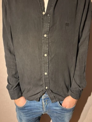 Svart skjorta från Les Deux - Säljer en svart skjorta från Les Deux i storlek L. Skjortan har klassisk krage, knappar framtill och långa ärmar. Materialet är mjukt och är bomull, perfekt för en clean och avslappnad stil. Diskret broderad logga på bröstet.