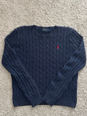 Kabelstickad Ralph Lauren tröja - Kabelstickad Ralph Lauren tröja som är blå med röd häst, som är i storlek S. Hör av er vid frågor🙌