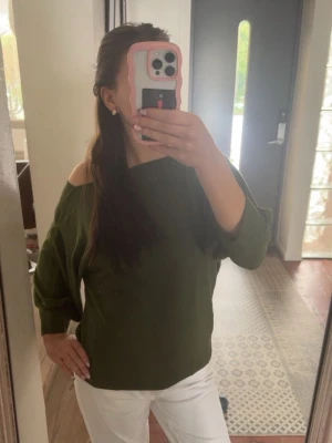 Olivgrön offshoulder topp från KappAhl - Snygg olivgrön offshoulder topp från KappAhl i ribbat material. Toppen har trekvartsärmar och en loose passform som ger en avslappnad vibe. Perfekt att styla med jeans eller kjol. 