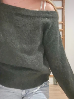 Mörkgrön offshoulder stickad tröja - Mysig mörkgrön stickad tröja från Gina Tricot med offshoulder-modell. Tröjan har lång ärm och en lite lös passform som ger en avslappnad vibe. Perfekt till jeans och funkar året runt när du vill vara både bekväm och snygg.