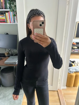 Svart ribbad långärmad topp BikBok - En svart, ribbad långärmad topp från BikBok i storlek S. Toppen har en tight passform och är tillverkad i ett mjukt och stretchigt material som sitter snyggt på kroppen. Perfekt att styla med jeans eller kjol för en clean look.