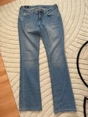 Ljusblå bootcut jeans från Lee - Säljer ett par ljusblå jeans från Lee med klassisk femficksdesign och bootcut-ben. Jeansen har normal passform och är tillverkade i mjukt denimtyg av bomull. Perfekta för dig som gillar en avslappnad och tidlös look.Storlek W30 L33