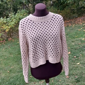 Stickad tröja - Säljer en beige stickad tröja från H&M Divided i storlek S. Tröjan har ett snyggt hålmönster och ribbade muddar vid hals, ärmslut och nederkant. Perfekt för lager-på-lager och chill höst- eller vinterstil🍂🤎 Knappt använd! Det är bara att skriva om man har frågor!😊💖