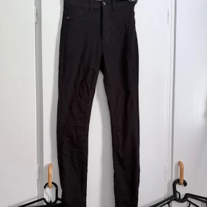 Svarta skinny jeans Gina Tricot Molly - Svarta Molly skinny jeans från Gina Tricot med klassisk femficksdesign och hög midja. Jeansen är stretchiga och sitter tight hela vägen ner, perfekta för dig som gillar en slimmad look. Materialet är mjukt och bekvämt, passar till allt.