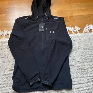 Under armour vindjacka  - Under armour vind jacka, helt ny aldrig använd inga märken, köpt i Frankrike i deras butik men den har aldrig kommit till användning. Ettiket är på. Storlek M 