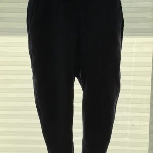 Nike svarta mjukisbyxor storlek L - Svarta mjukisbyxor från Nike i storlek L. Byxorna har dragsko i midjan, sidfickor och är tillverkade i mjukt bomullsmaterial. Perfekta för chill eller träning, med klassisk Nike-logga på insidan.