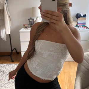 Vit bandeau topp  - Från Bik Bok och tidigare köpt på Vinted, aldrig använd av mig. I strl S och väldigt bra skick. Finns en dragkedja i sidan och hela toppen fylls av utstickande blommor