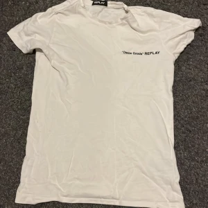Vit t-shirt från Replay - Vit t-shirt från Replay med svart text 'Denim Goods' på bröstet. Klassisk passform med rund hals och korta ärmar. Tillverkad i mjuk bomull, perfekt för en clean och enkel stil.