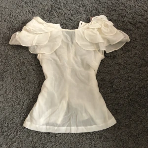 Vit blus med volangaxlar - Säljer en jättesöt blus med volanger på axlarna. Den passar perfekt till ett par jeans eller en kjol🥰