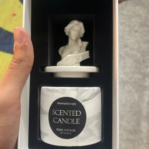 Aromatherapy Scented Candle Rose Cottage - Elegant aromatherapy doftljus i marmorerad behållare, med dekorativ byst på locket. Perfekt för avkoppling och heminredning. Produkten ser oanvänd ut och levereras i originalförpackning.