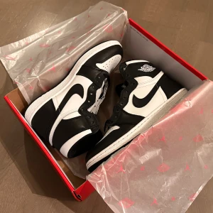 Nike Air Jordan 1 85 retro high svart/vit 42.5 - Säljer ett par Nike Air Jordan 1 i svart och vitt skinn. Klassisk high-top siluett med svart swoosh, snörning och vit yttersula. Ikonisk Air Jordan-logga på sidan. Perfekta för dig som vill ha en clean och tidlös sneaker med streetkänsla.