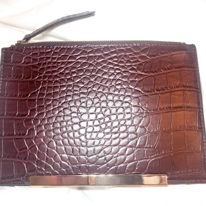 2 st Svart och brun kuvertväska i skinn - Snygg kuvertväska med ena sidan i mörkbrunt krokopräglat skinn och andra sidan i svart quiltat skinn. Väskan har guldfärgade metalldetaljer och dragkedja upptill. Perfekt när du vill ha med det viktigaste och ändå se stilren ut.