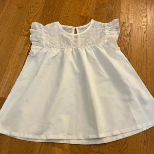 Vit blus med spets och volangärm - En söt blus med volang upptill och stängs med en knapp, aldrig använt 