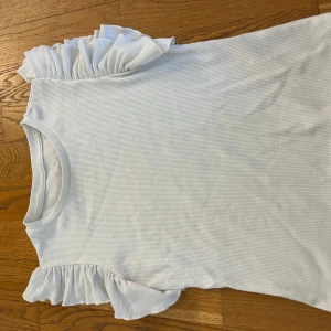 Vit ribbad topp med volangärmar - En t-shirt med ribbat typ och volang 