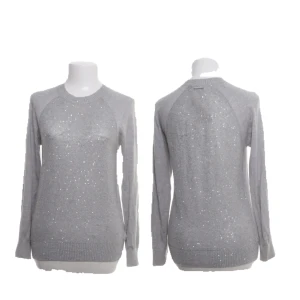 Grå glittrig stickad tröja Michael Kors - Superfin grå stickad tröja från Michael Kors med glittriga paljettdetaljer över hela tröjan. Långärmad modell med ribbade muddar och rund halsringning. Perfekt för dig som vill ha en snygg och bekväm tröja med lite extra bling.