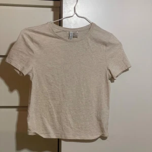 Beige basic t-shirt från Divided - Enkel och stilren beige t-shirt från Divided.  Använd en gång. Säljer den då den inte kommer till användning Tillverkad i mjuk bomull som känns skön mot huden. Perfekt att matcha med jeans eller kjol för en clean look. Pris kan diskuteras💞