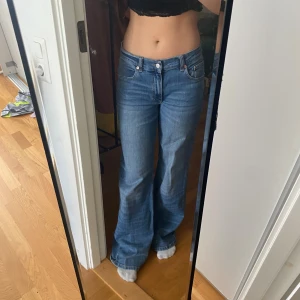 Blåa wide jeans med låg midja - Säljer ett par blåa jeans med låg midja och breda ben. Klassisk femficksmodell med snygga sömmar och bälteshällor. Jeansen har en avslappnad passform och är tillverkade i jeansmaterial. Perfekta för en chill och trendig look.