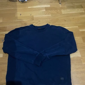 Mörkblå sweatshirt från Lee - En stilren mörkblå sweatshirt från Lee med rund hals och långa ärmar. Tröjan är tillverkad i en mjuk bomulls- och polyestermix och har en diskret Lee-logga nertill. Perfekt för en chill och enkel look.