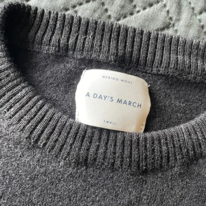 Svart merinoulltröja A Day's March S - Klassisk svart stickad tröja från A Day's March i mjuk merinoull. Rund halsringning med ribbade muddar vid hals, ärmslut och nederkant. Perfekt för lager-på-lager och enkel att matcha med allt.