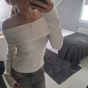 Offshoulder ribbad topp från H&M - Superfin offshoulder topp från H&M i ribbad, mjuk och stretchig kvalitet. Toppen är ljusbeige, har långa ärmar och sitter snyggt figurnära. Perfekt för dig som gillar en stilren och trendig look.