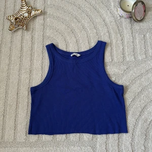 Blå ribbad croppad linnetopp - Säljer en blå croppad linnetopp från Gina Tricot. Toppen är ribbad och har breda axelband samt rund halsringning. Perfekt för dig som gillar en enkel men snygg stil.