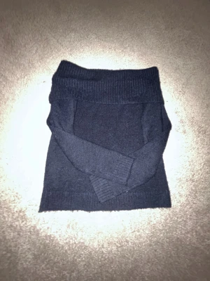 Mörkblå offshoulder stickad  - Snygg mörkblå stickad tröja från Gina Tricot med bred ribbad kant upptill som ger en offshoulder-look. Tröjan har långärmade ärmar och är mjuk och skön, perfekt för kyliga dagar. 