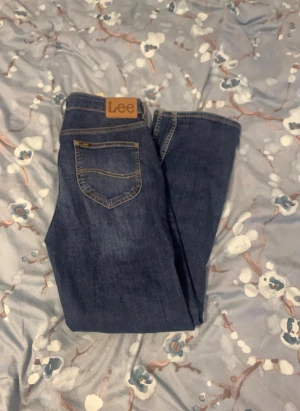 Mörkblå raka jeans från Lee - Snygga mörkblå jeans från Lee med klassisk rak passform. Jeansen har fem fickor, kontrastsömmar och Lee-lapp bak i midjan. Perfekta för dig som gillar en tidlös och enkel stil. Tillverkade i slitstarkt denimtyg.