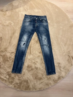 Dsquared2  jeans med slitningar - Snygga blå  jeans från Dsquared2 med slitna detaljer och färgstänk. Klassisk femficksmodell, låg midja och smal passform. Jeansen har en tvättad look och är tillverkade i stretchig denim för extra komfort. Perfekt för dig som gillar streetstyle. Kom dm för eventuella frågor🧐pris kan diskuteras 💯. 