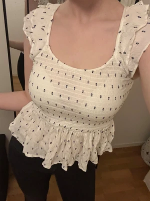 Snygg kortärmad volangblus - Smickrande blus köpt på Vero Moda med en jättefin baksida. Tight passform och stretchigt material.