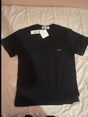 Svart t-shirt från Comme des Garçons Play - Svart t-shirt från Comme des Garçons Play med det ikoniska hjärta med ögon broderat på bröstet. Storlek M men sitter som en M. Helt ny. Hör av er vid intresse!!